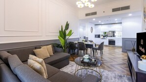 En moderne stue med sofa, sofabord og et spiseområde i baggrunden.