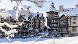 En snötäckt byggnad med en traditionell arkitektonisk stil, en skidlift och en klar himmel.