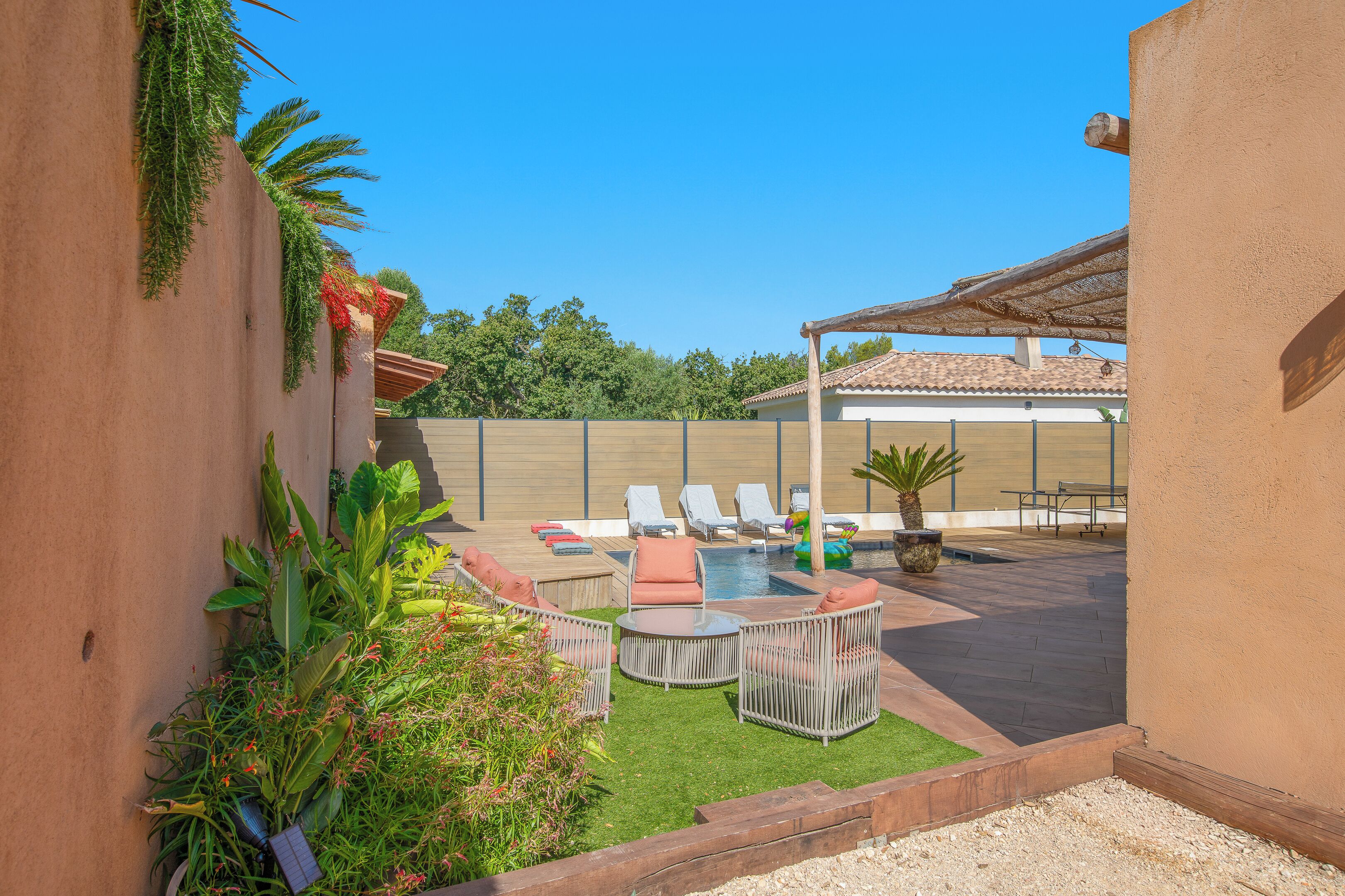 Ein Garten mit Pool, Liegestühlen und einer Pergola.
