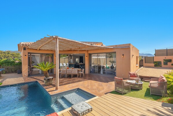 Uma casa moderna com piscina, móveis de exterior e pérgula.