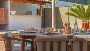 Een terras met zwembad, houten meubels en een pergola.
