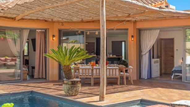 Een zwembadgedeelte met een pergola, een eettafel en een bloempot.