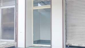 A corner of a building with a sliding glass door, a glass door with a metal frame, and a closed roller shutter. - Saver Double Hotel O Chandigarh Road (Dera Bassi)