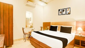 A hotel room with a bed, a desk, a chair, an air conditioning unit, a mirror, and framed artwork on the wall. - Saver Double Hotel O Chandigarh Road (Dera Bassi)