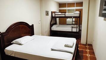 A room with a single bed, a bunk bed, and a small bathroom.