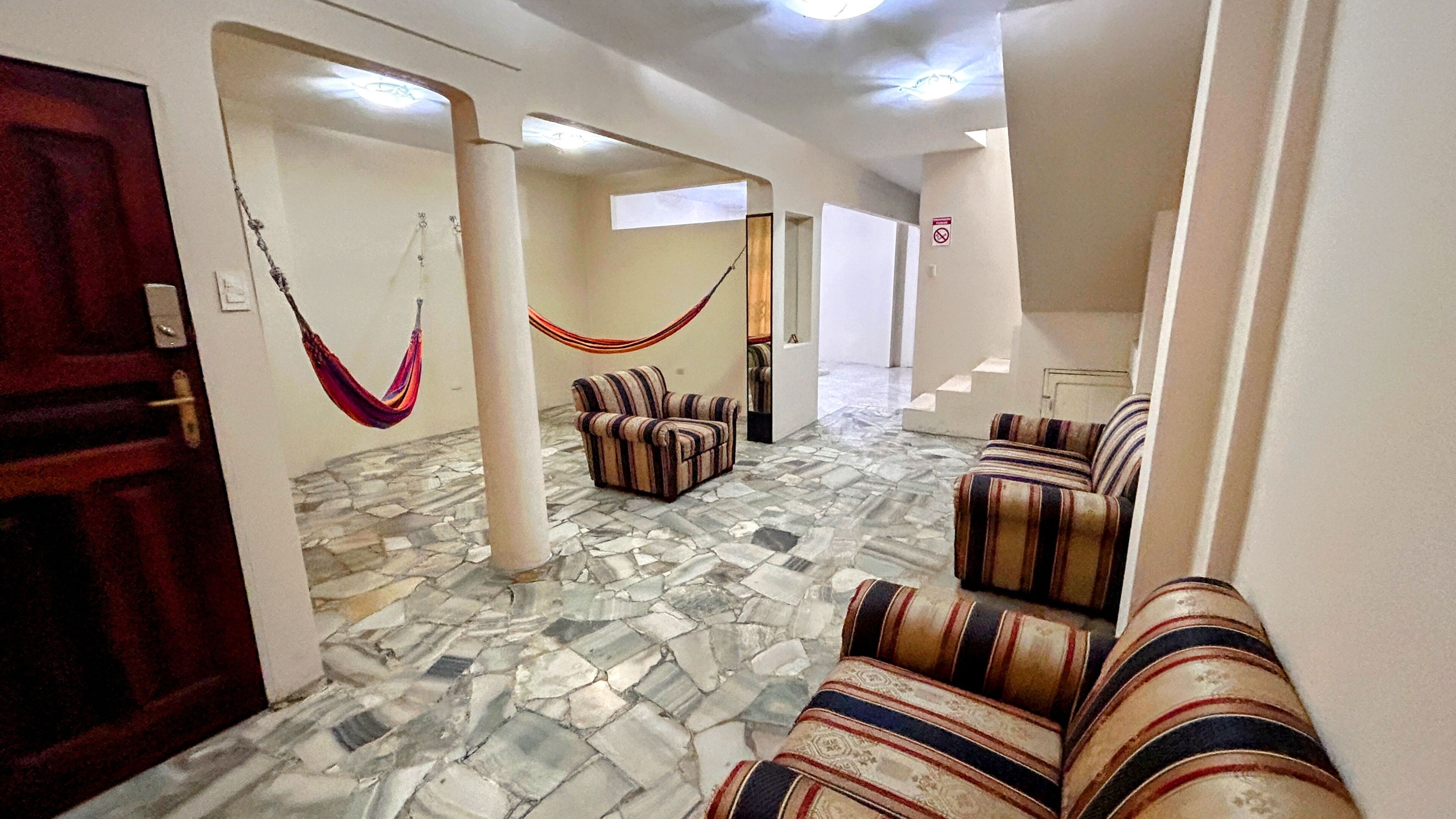A hallway with a stone floor, striped sofas, and a hammock.