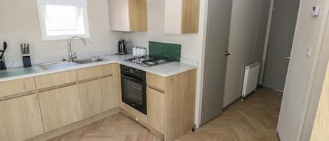 Une cuisine moderne avec des meubles en bois, un four encastré, un évier et une fenêtre.