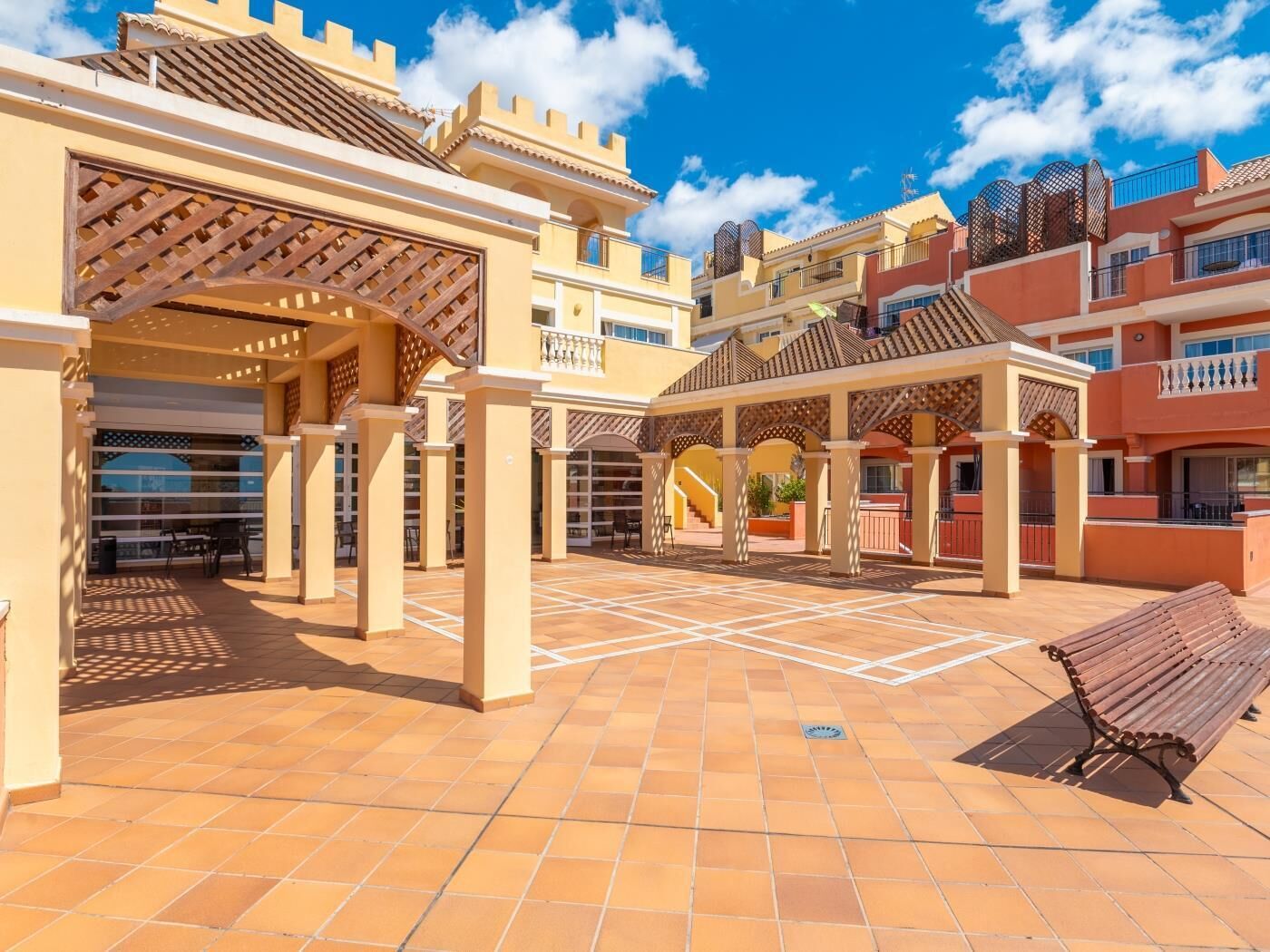 A courtyard with a covered seating area, a staircase, and a pool.