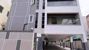 Um edifício moderno com telhado plano, grandes janelas e área de estacionamento coberta.