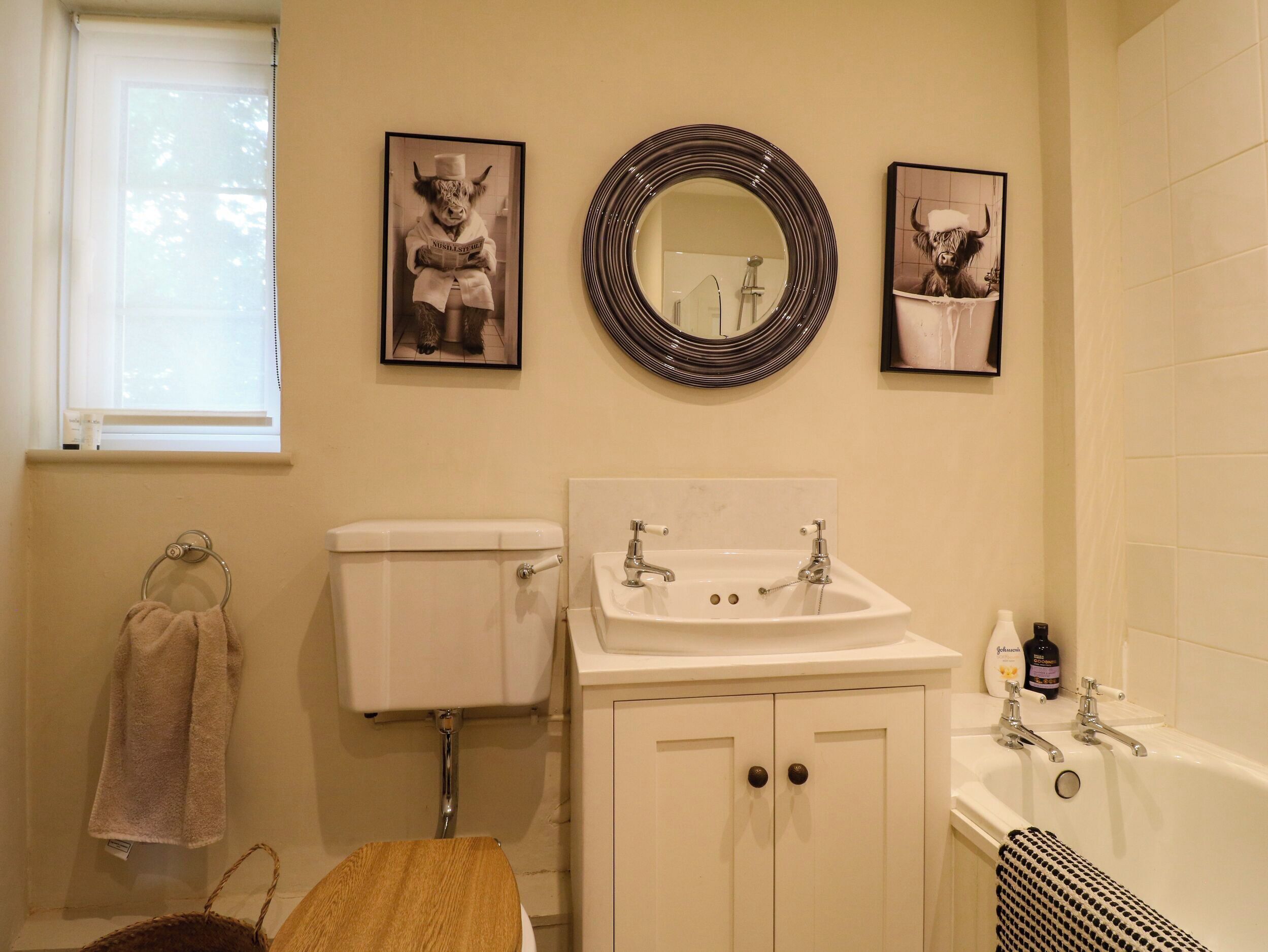 Une salle de bain avec des toilettes, un lavabo et une baignoire. Des tableaux encadrés ornent le mur.
