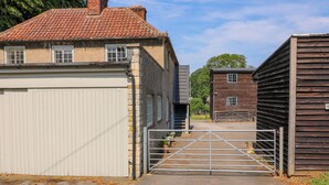 Un camí d'accés tancat per una reixa que condueix a un edifici amb teulada d'estries i un garatge.