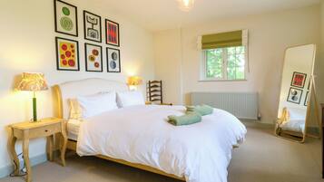 A bedroom with a bed, bedside tables, a mirror, a window, and wall art.