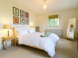 Un dormitorio con cama, mesitas de noche, un espejo, ventana y decoración en la pared.