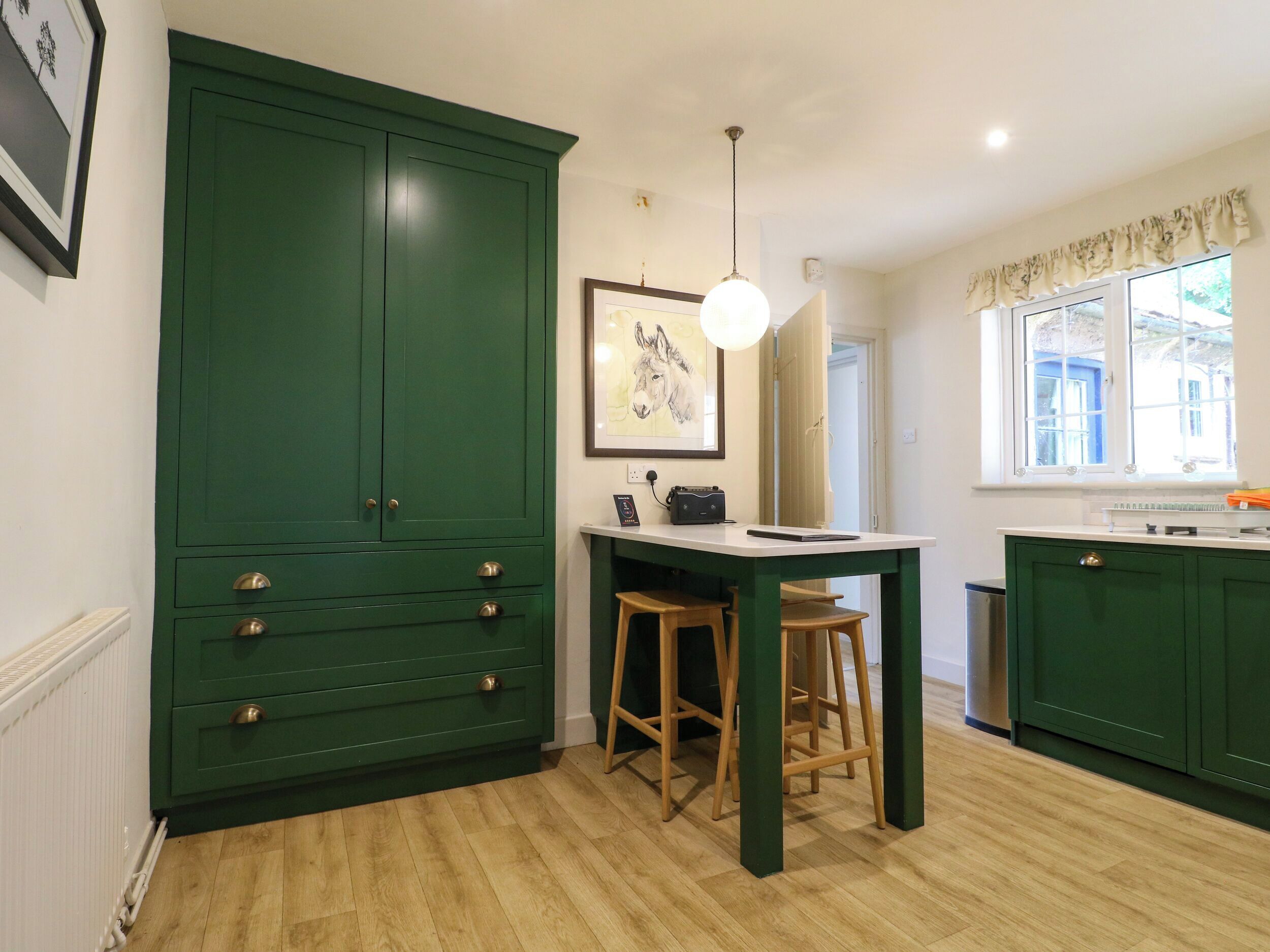 A kitchen with green cabinets, a wooden table, and a window with a view.