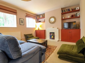 A living room with a sofa, a television, a fireplace, and bookshelves. - The Stable Flat (Melton Mowbray)
