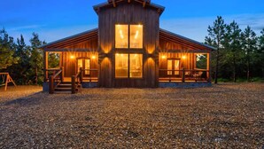 A wooden cabin with a covered porch and large windows. - Sweet Sunrise | Luxury Cabin w/ Slide, Hot Tub & Views (Broken Bow)