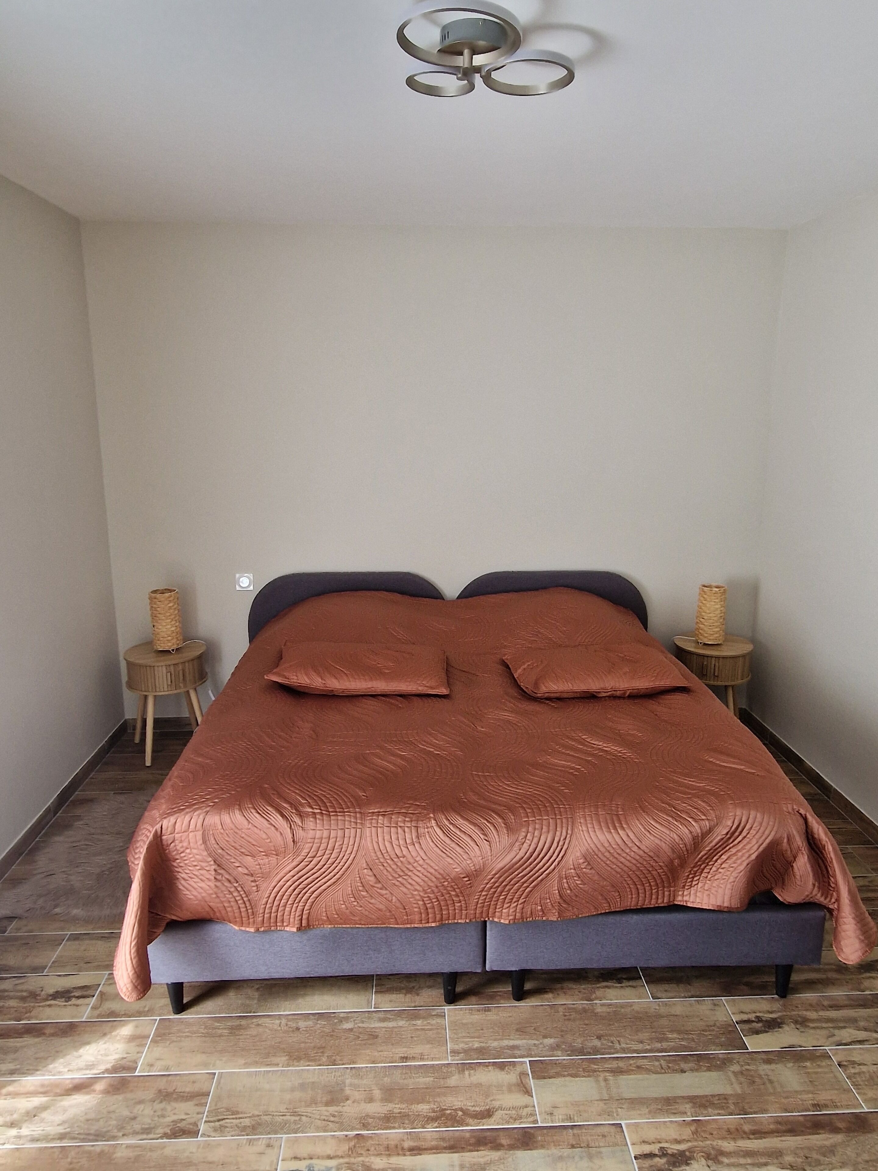 A bedroom with a bed, two nightstands, a ceiling fan, and a tiled floor.