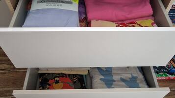 A drawer with folded clothes, including a label for 'Drap house 90x190+25cm'.