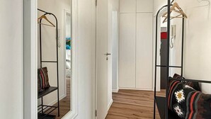 A hallway with a mirrored closet, a bench with pillows, and a wooden floor.