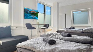A bedroom with a bed, a desk, a chair, and a TV.