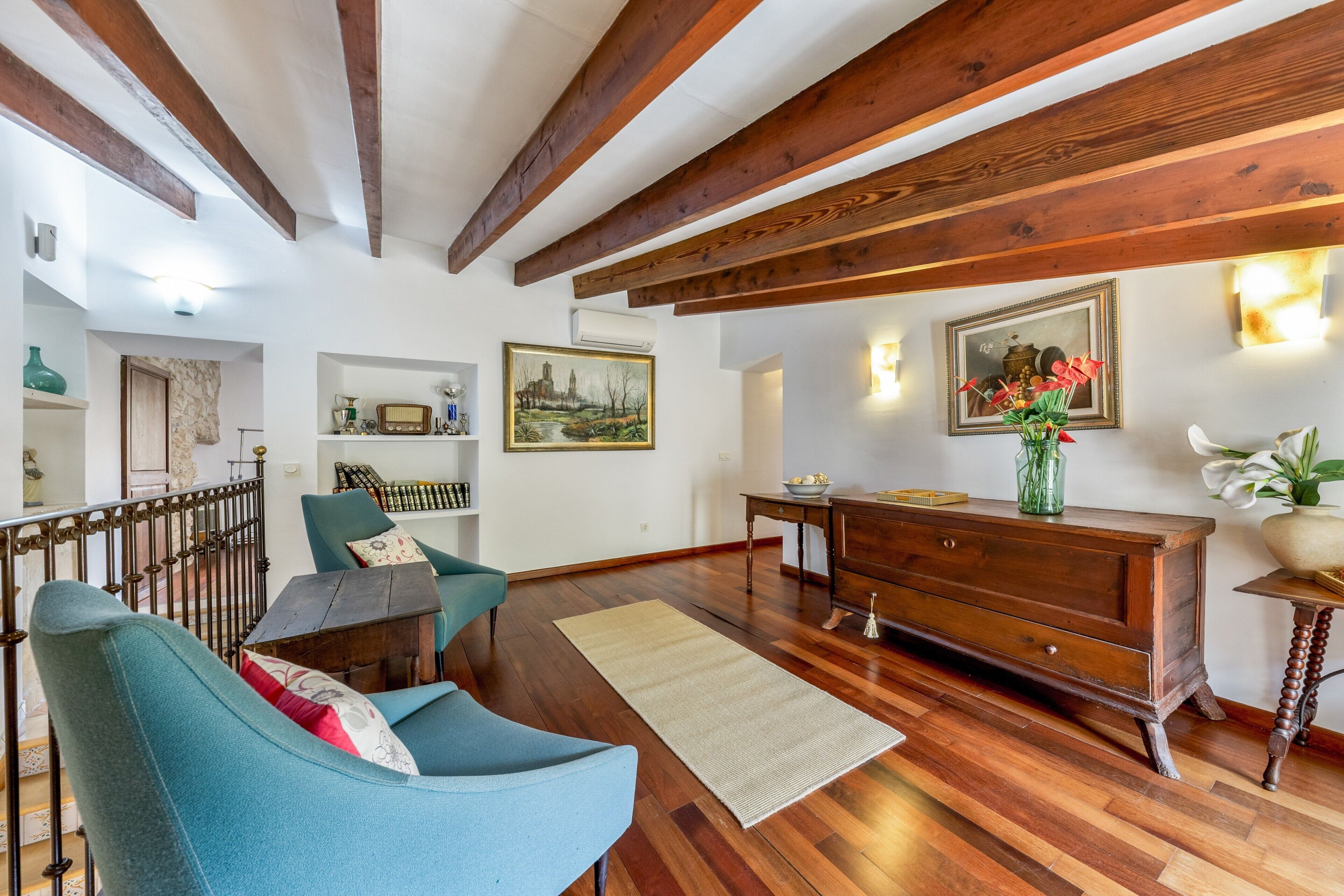 Una sala de estar con sofá, piso de madera y un cuadro en la pared.