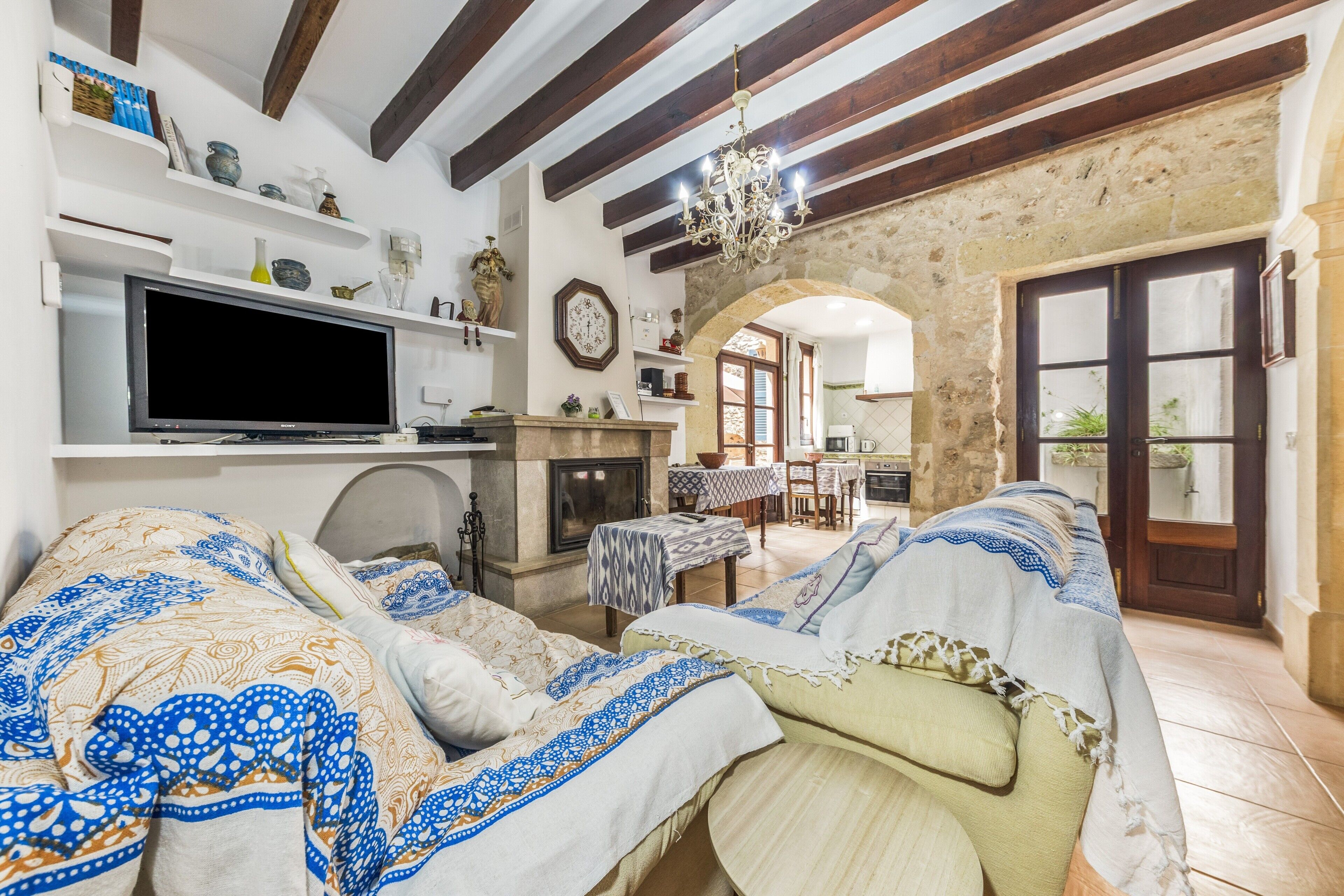 Una sala de estar con chimenea, sofá, televisión y paredes de piedra.