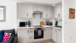 A compact kitchen with white cabinets, a microwave, toaster, and oven. - Shoreditch Studio Flat near Brick Lane & Liverpool St with Wi-Fi, Washer & Dryer (London)