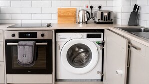 A compact kitchen with a built-in oven, a washing machine, and a toaster. - Shoreditch Studio Flat near Brick Lane & Liverpool St with Wi-Fi, Washer & Dryer (London)