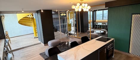 A modern kitchen with a marble countertop, wooden flooring, and a dining area with a yellow accent wall.