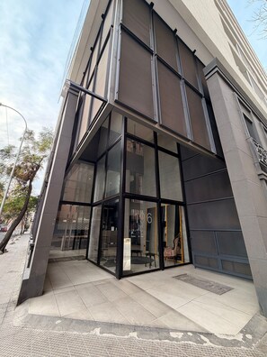 A modern building with a glass entrance, large windows, and a visible door number. - Colección R Boutique (Santiago)