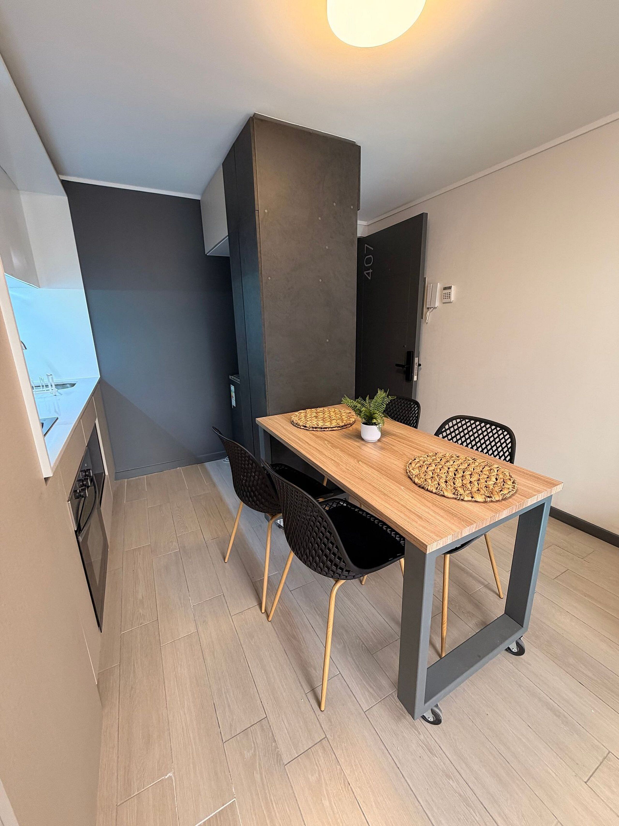 Un comedor pequeño con una mesa de madera, sillas negras y una planta en maceta.