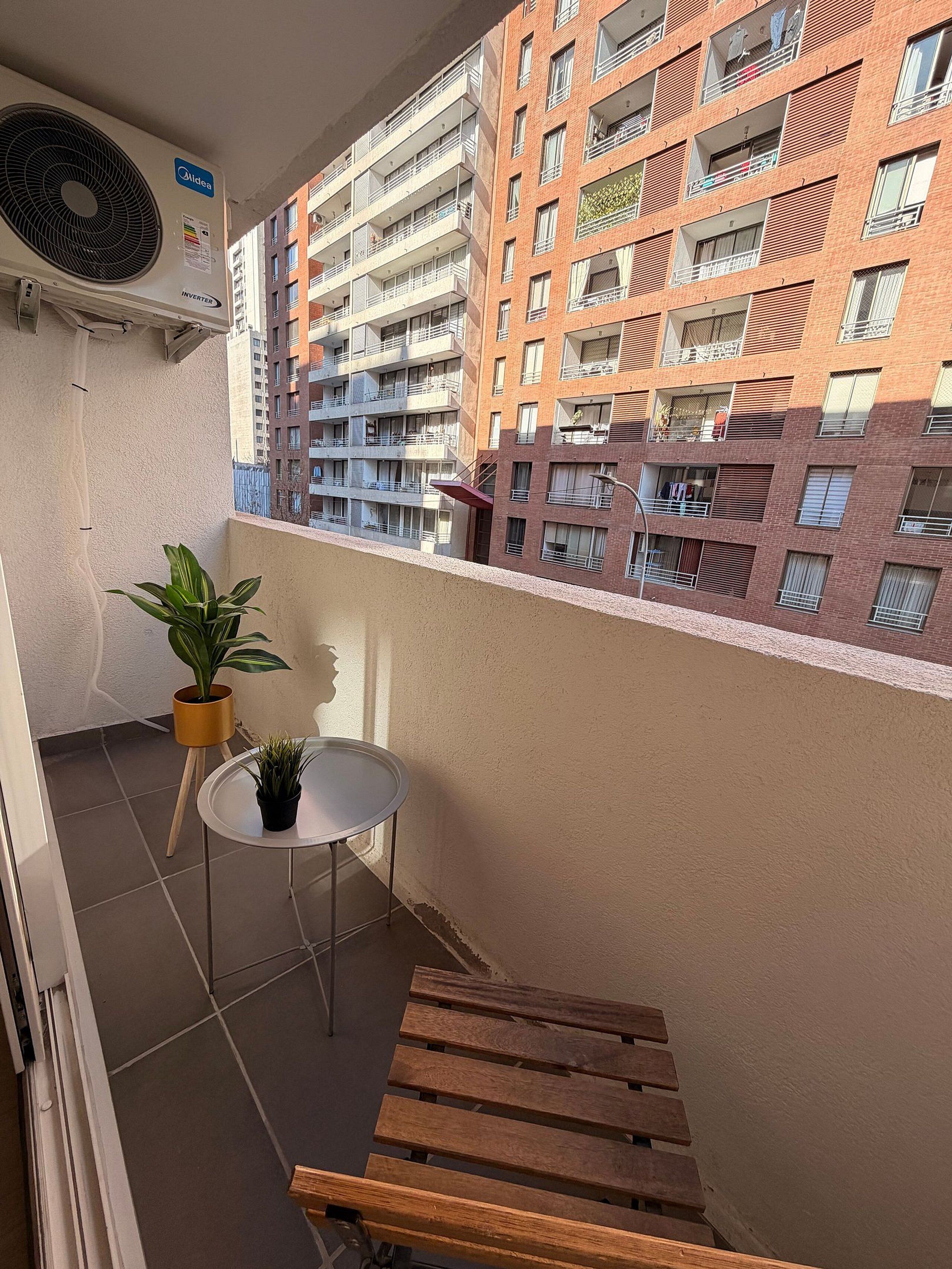 Ein Balkon mit Tisch, Blumentöpfen und einer hölzernen Bank.