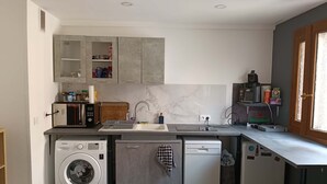 Cocina compacta con lavadora, lavavajillas, microondas y un refrigerador pequeño.