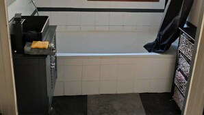 Un baño pequeño con bañera, ventana, toallero y retrete.