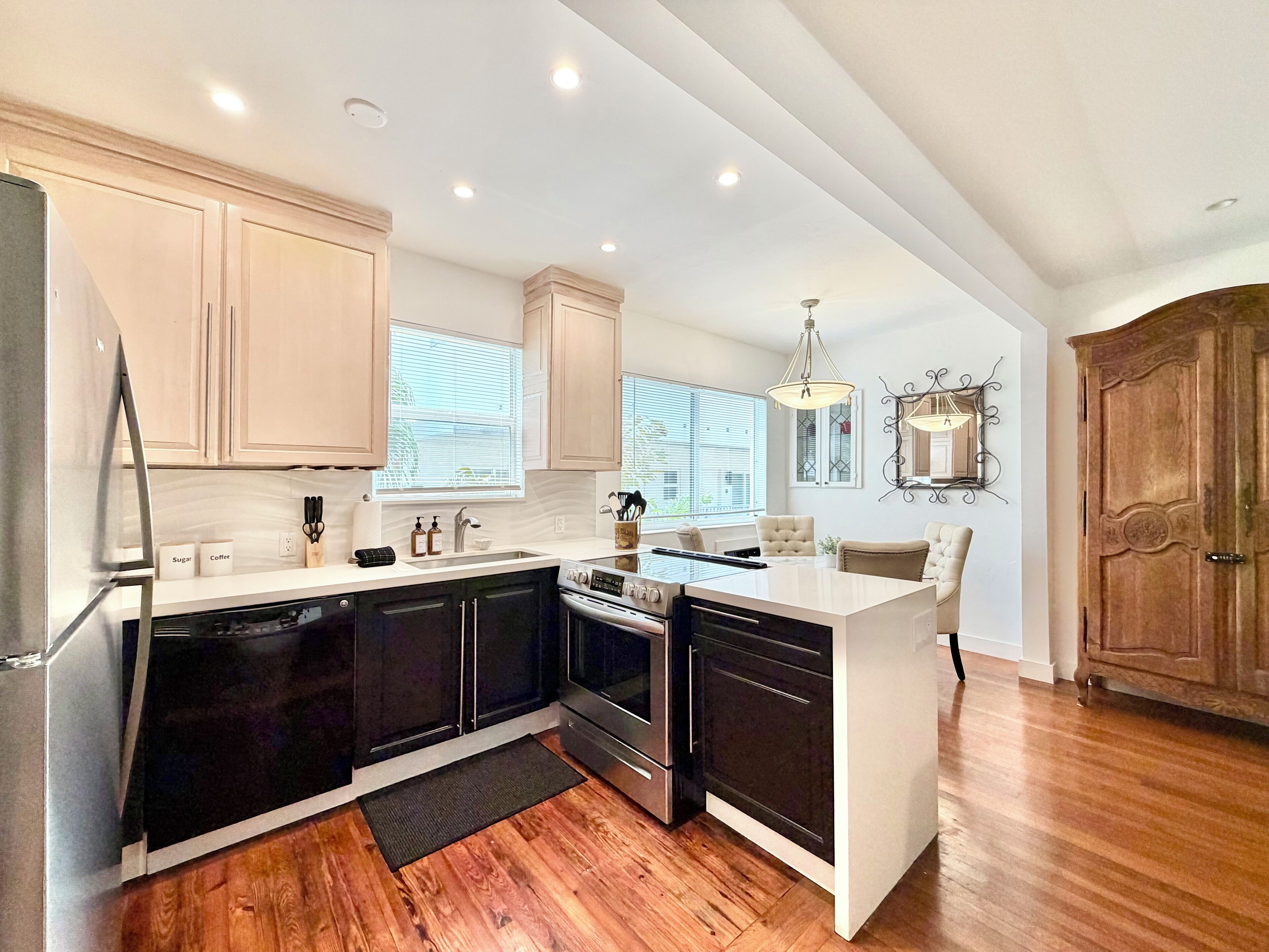 A modern kitchen with a central island, built-in appliances, and a dining area with a chandelier.