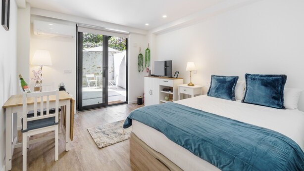 A bedroom with a bed, desk, chair, and a sliding glass door leading to an outdoor area. - The Archway Studio by Minho s Guest (Braga)