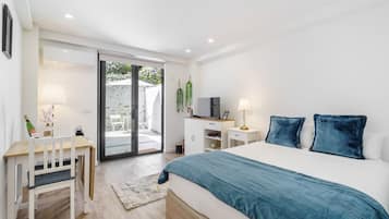 A bedroom with a bed, desk, chair, and a sliding glass door leading to an outdoor area.