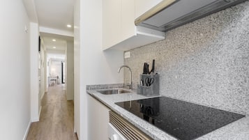 A modern kitchen with a granite countertop, stainless steel sink, and a range hood.