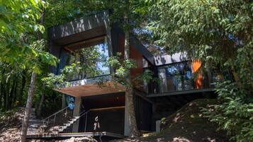 A modern multi-level house surrounded by dense forest.