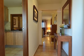 A hallway with a kitchen area on the left, a dining area with a table and chairs, and a mirror on the right. - Solmares Las Palmeras 124 (Punta del moral)