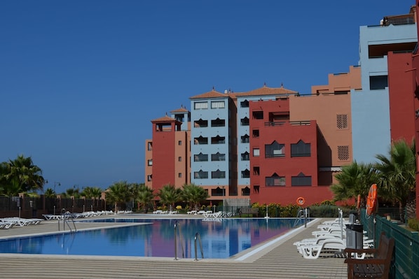 A hotel with a swimming pool, multiple balconies, and palm trees. - Solmares Las Palmeras 124 (Punta del moral)