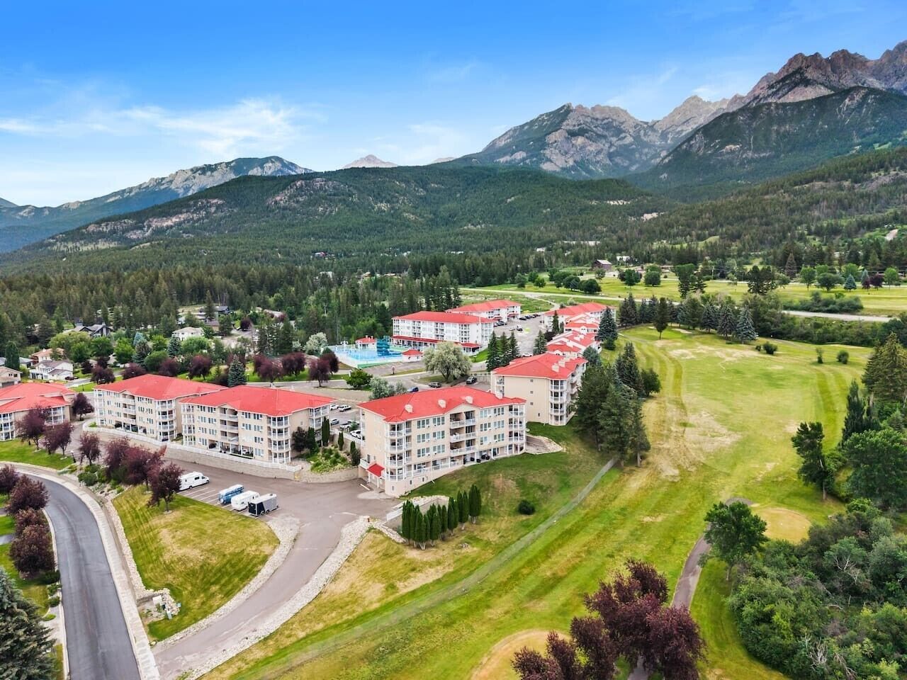 Um conjunto habitacional com vários edifícios, uma estrada e montanhas ao fundo.