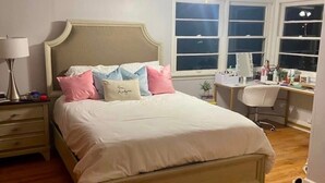 Une chambre à coucher comprenant un lit, un bureau, une chaise, un ventilateur de plafond et une fenêtre.