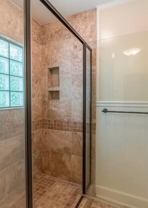 A shower with a glass door, a tiled wall, and a window with a decorative pattern. - Delightful 3-bedroom house with AC in charming Starkville (Starkville)