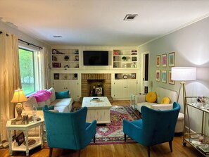A living room with a fireplace, a television, and a bookshelf. - Delightful 3-bedroom house with AC in charming Starkville (Starkville)