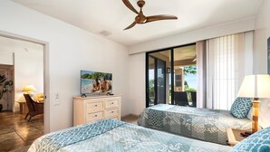 A hotel room with two beds, a TV, a ceiling fan, a sliding glass door to a balcony, and a small table with a lamp. - Waikoloa Fairways #a101: Golf Course Ocean Views! (Waikoloa)