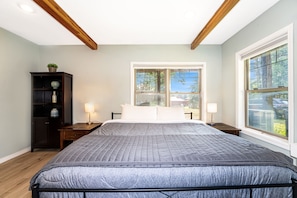 Um quarto com uma cama grande, uma mesa de cabeceira, um penteado e uma janela com vista para o exterior.