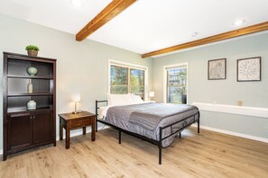 Ein Schlafzimmer mit einem Bett, einem Nachttisch, einer Kommode und zwei Fenstern.