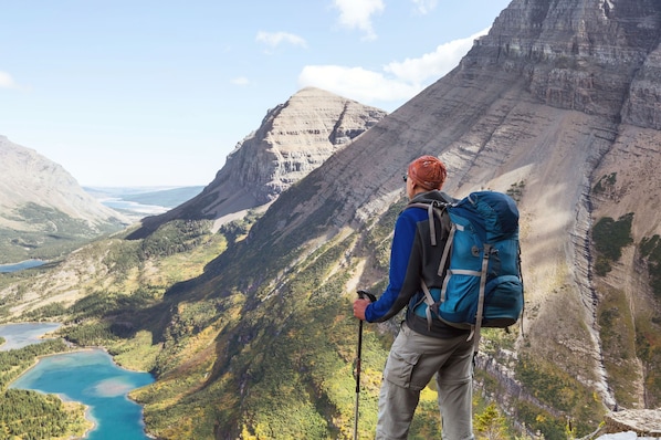 A person hiking with a backpack, overlooking a mountainous landscape with a lake. - Glacier Gateway Lodge | Hot Tub & Firepit (Hungry Horse)