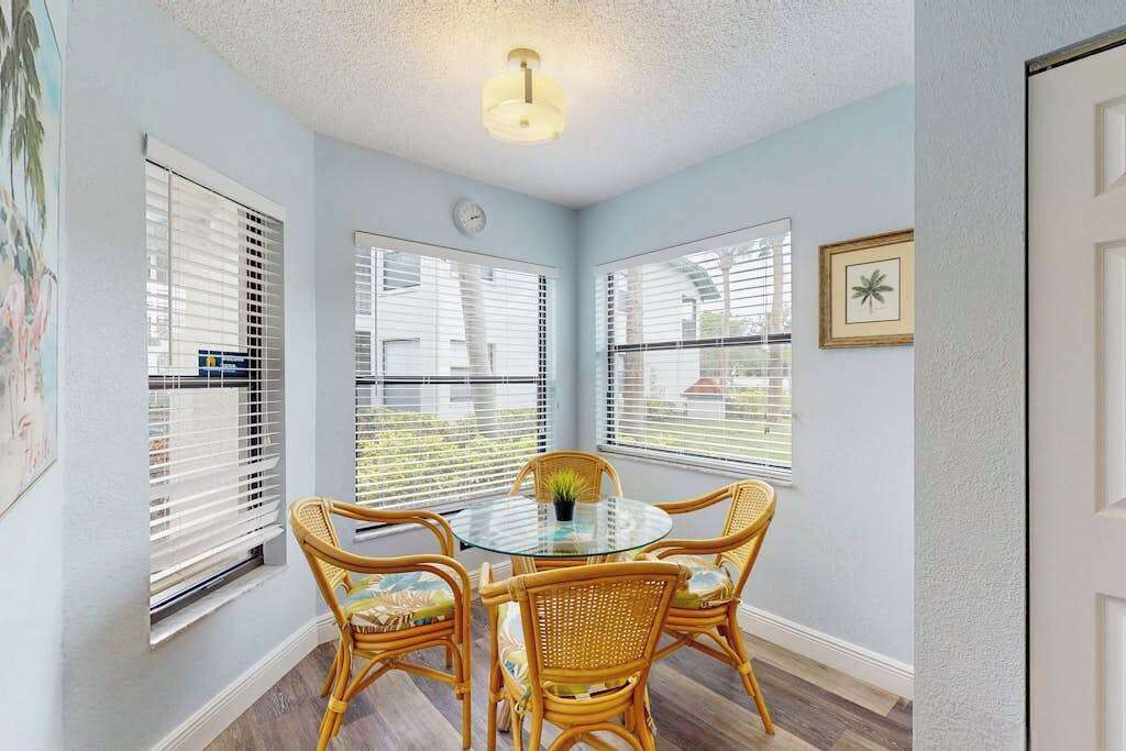 A room with a round glass table, wicker chairs, and a ceiling light fixture.